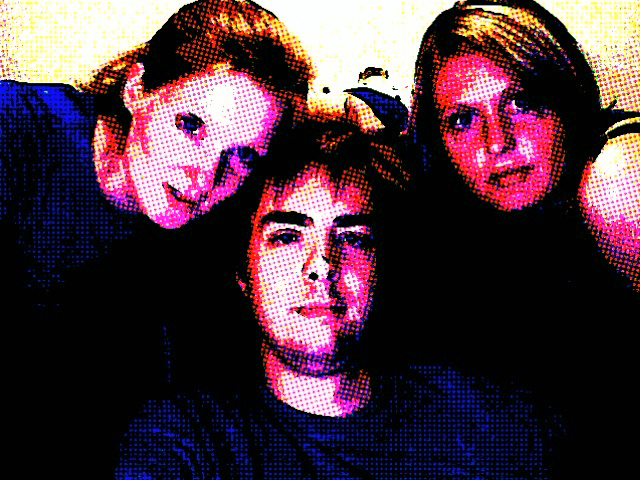 Three people pose closely together for a photo booth picture with a colorful, high-contrast filter applied.