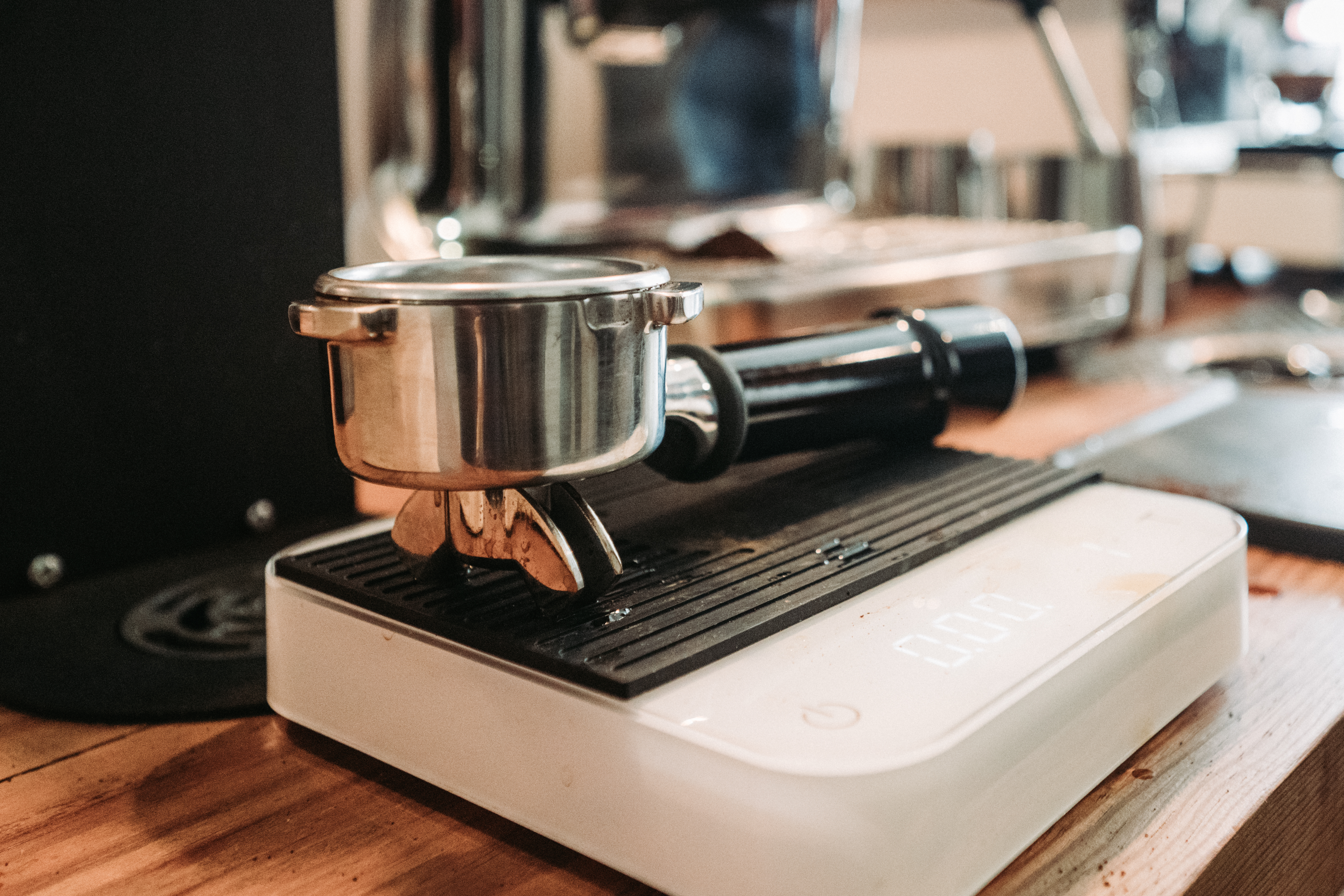 A portafilter and tamper rest on a digital scale during a barista training session.