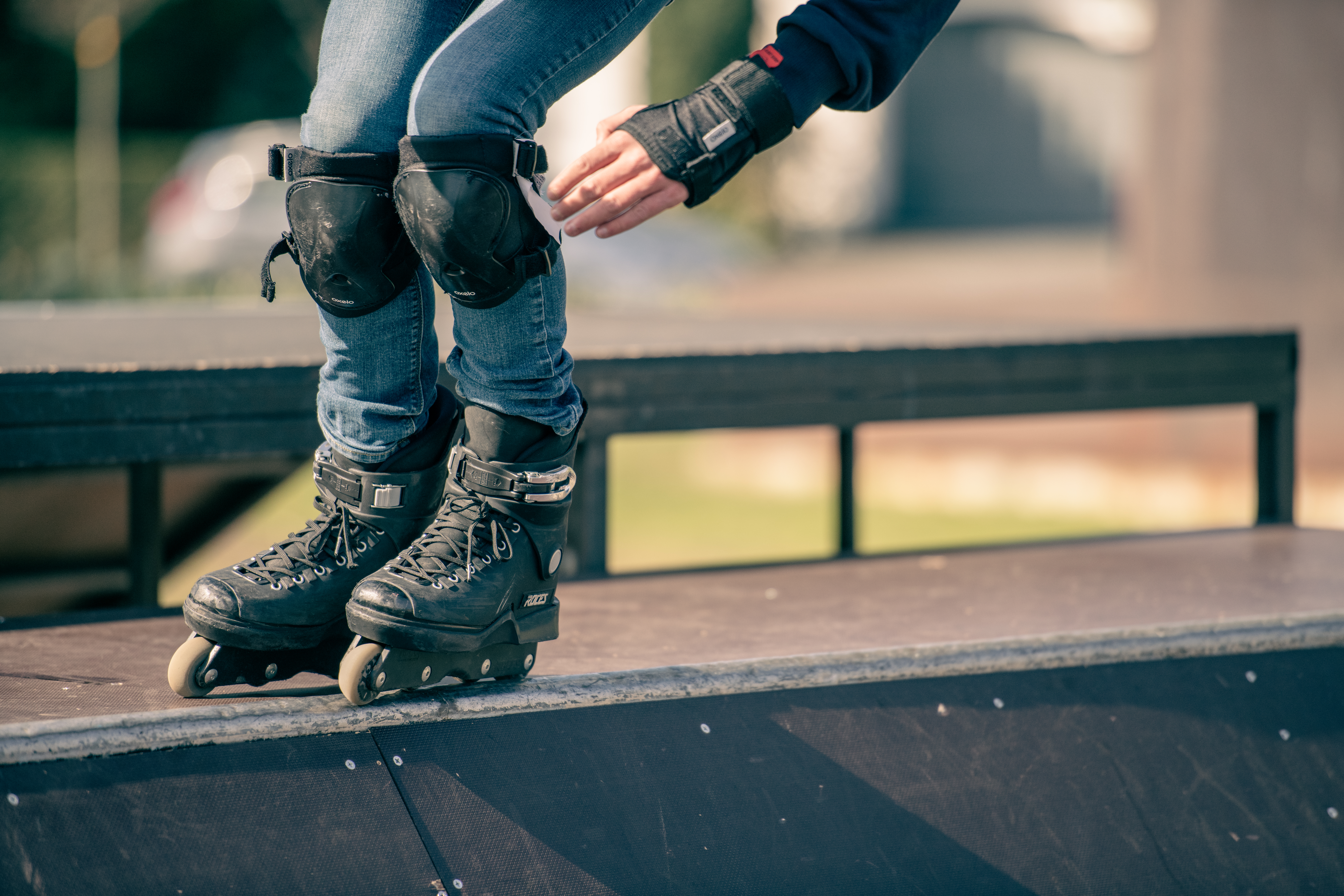 A person wearing rollerblades and protective gear balances on the edge of a skate park ramp.