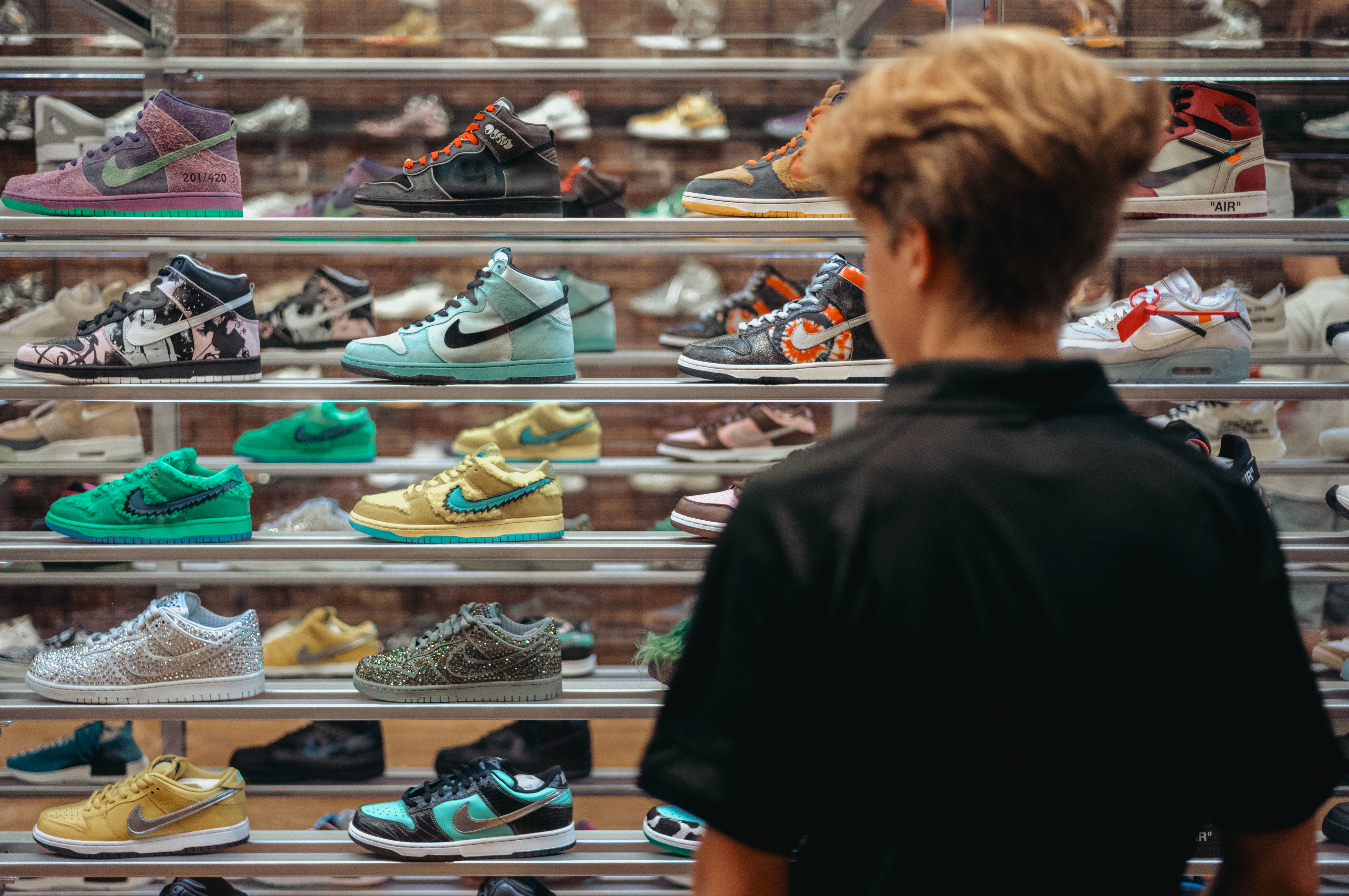 A young man stands in front of sneakers in a glass case.
