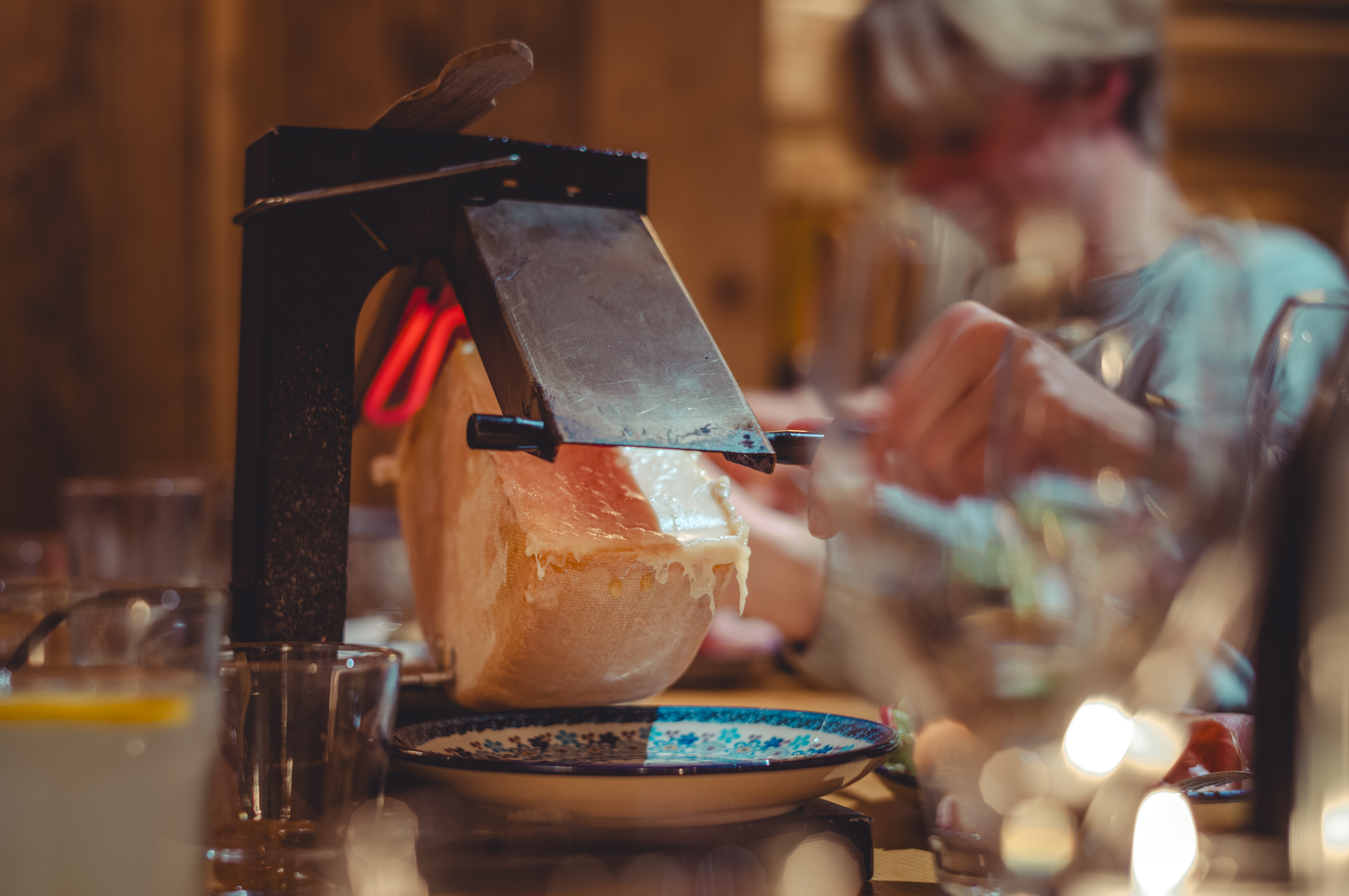 A traditional French raclette grill with melting cheese, scraped onto a plate.