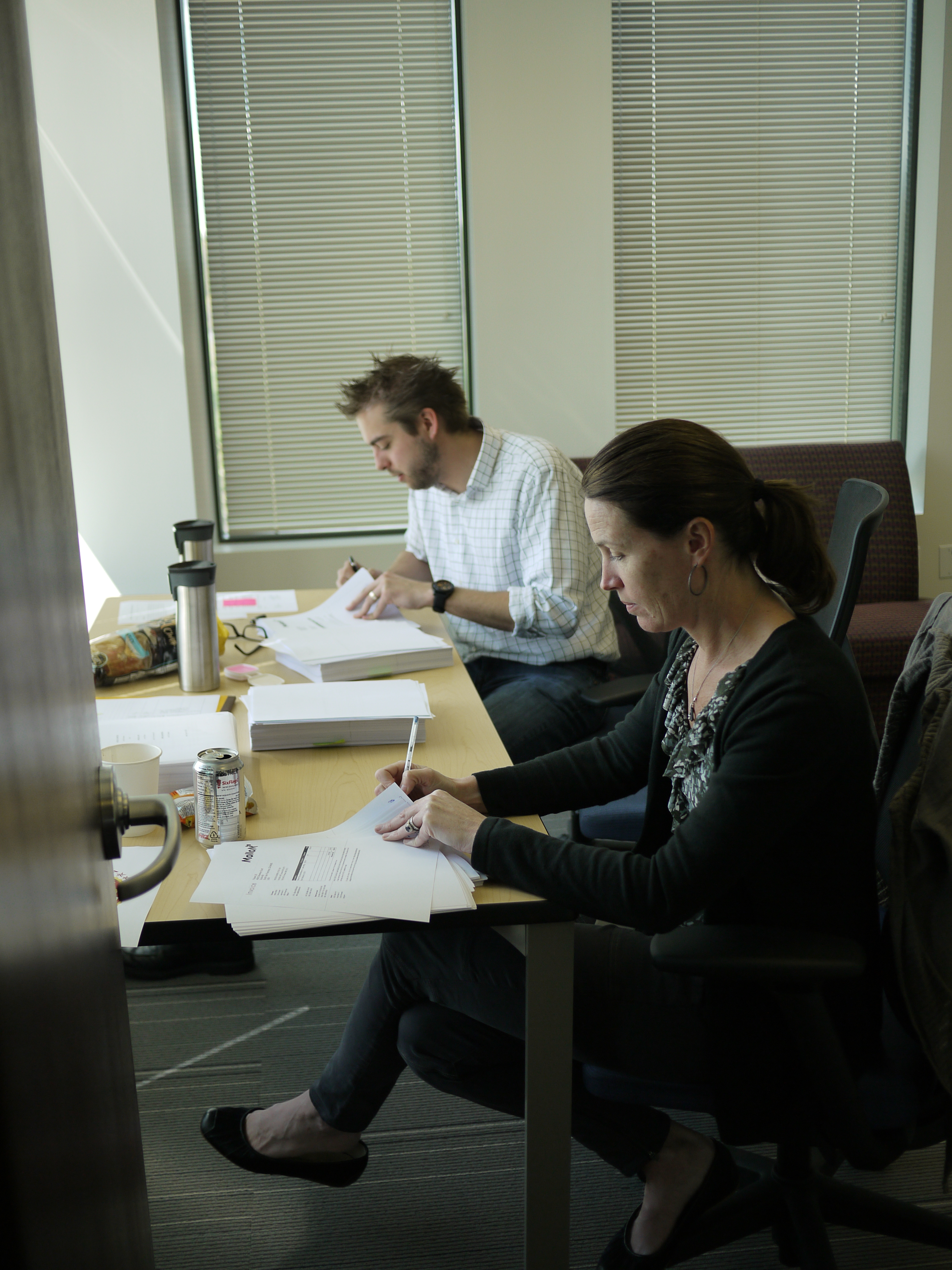 Two people sit at a table reviewing and signing documents, possibly related to the closing of Mollom.