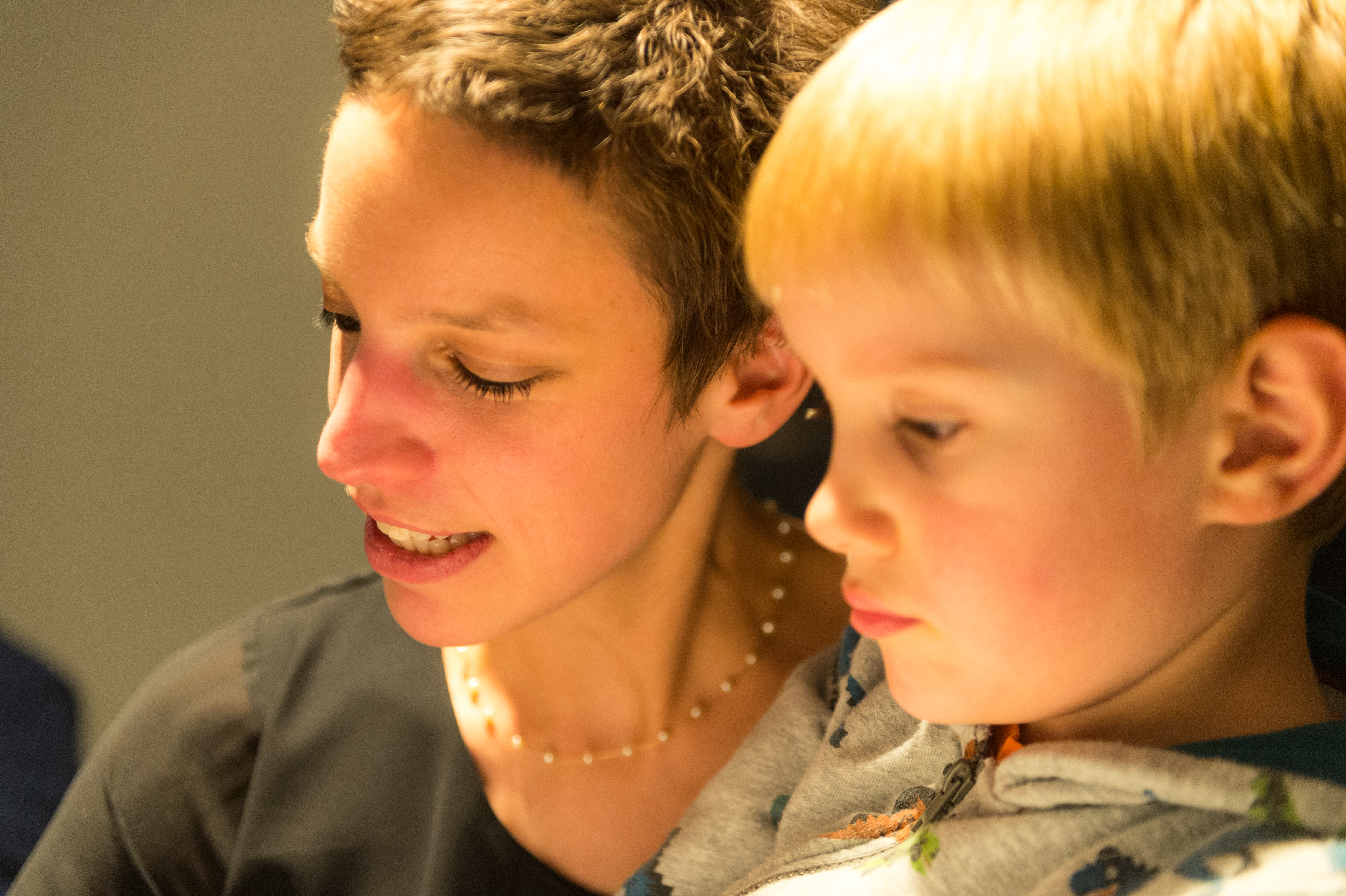 A woman and a young child sit closely together, both focused on something in front of them.
