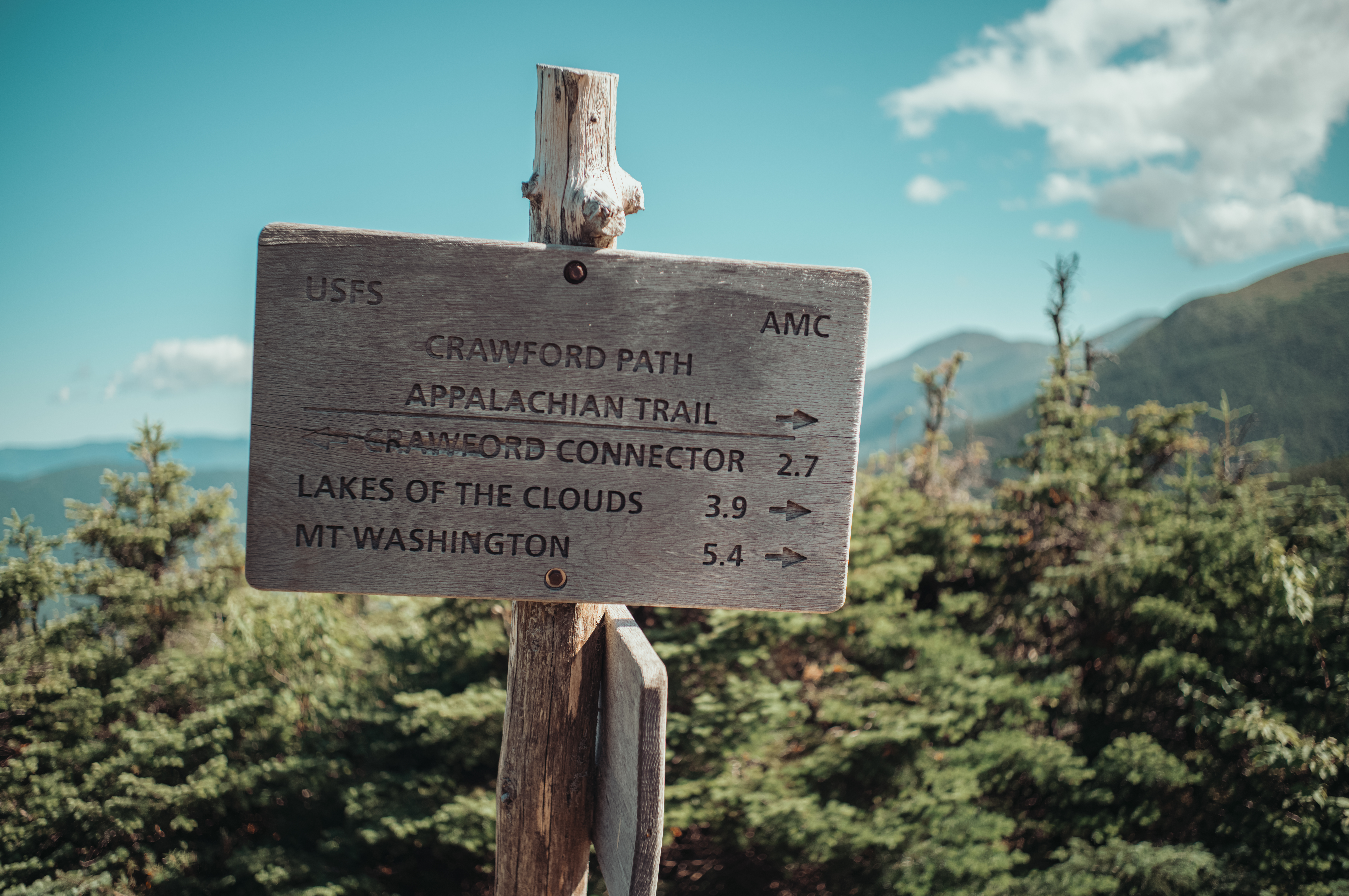 A wooden trail sign marks the Crawford Path and Appalachian Trail, with Mount Washington 5.4 miles away and Lakes of the Clouds 3.9 miles away.