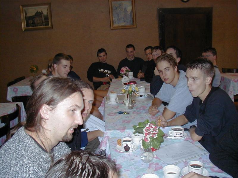A group of people sitting around a table with tea and snacks, engaged in conversation.