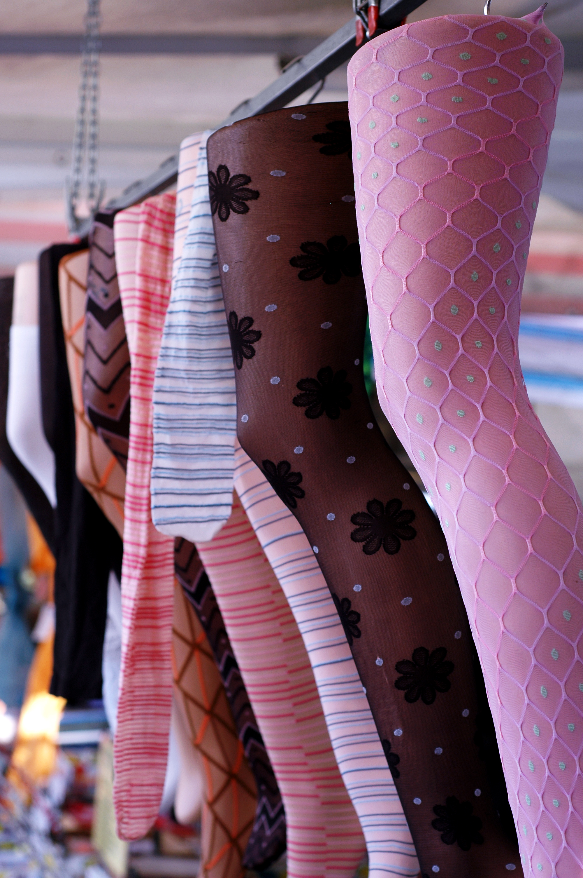 Mannequin legs wearing colorful patterned stockings hang in a row at a market display.