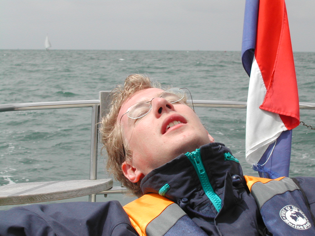 A person wearing a life jacket leans back on a boat with eyes closed, appearing relaxed.