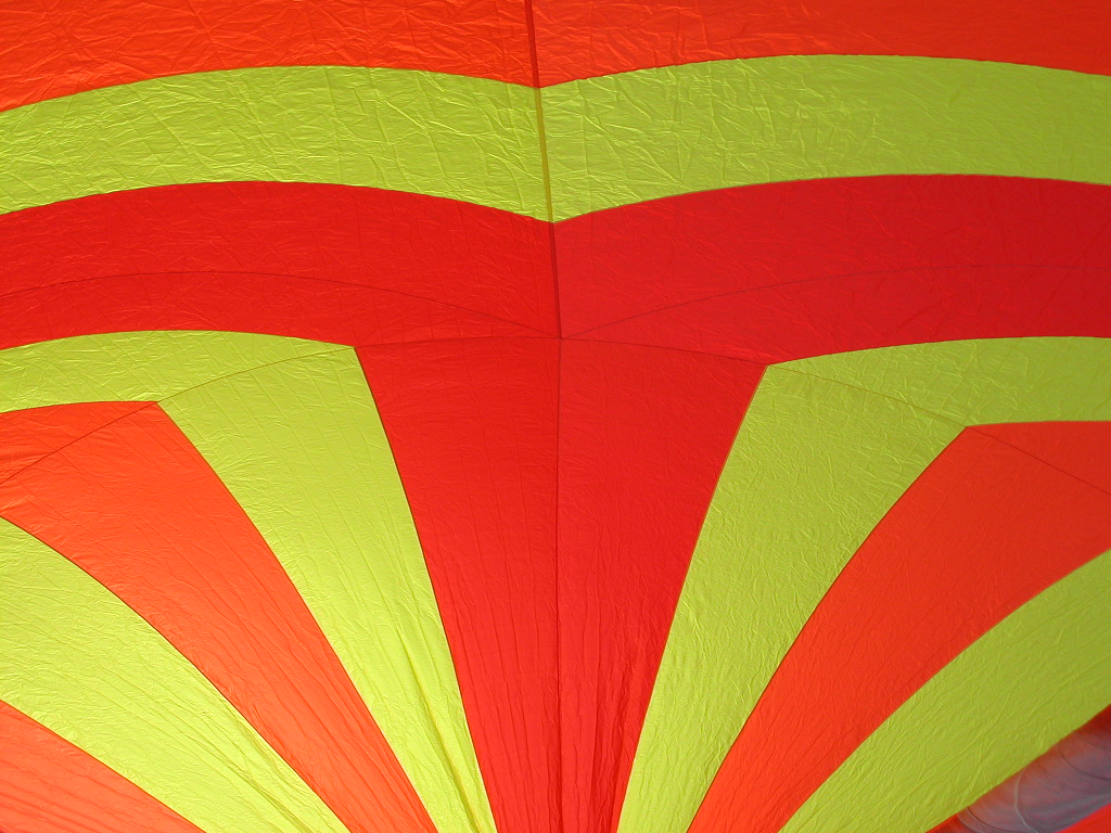 Close-up of a colorful kite with red and yellow fabric panels stretched tightly in the wind.