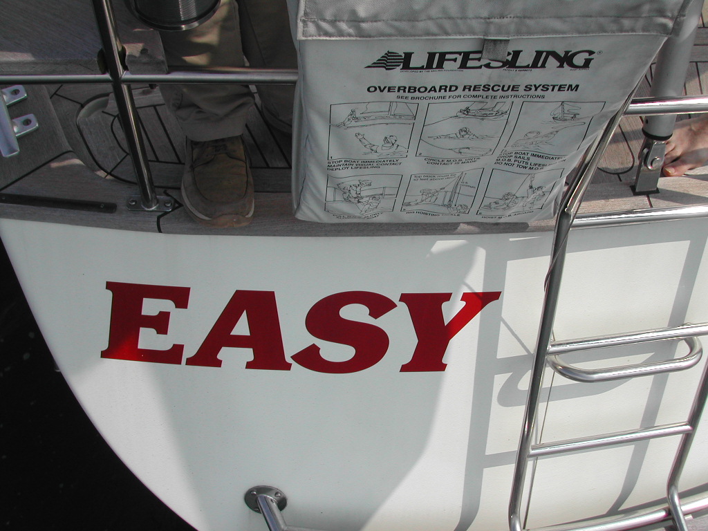 The back of a boat named "EASY" with a rescue system bag attached and a metal ladder leading down.