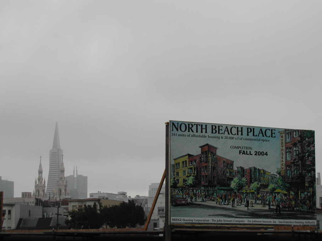 A large billboard advertises the North Beach Place housing project, with San Francisco skyscrapers and churches in the background.