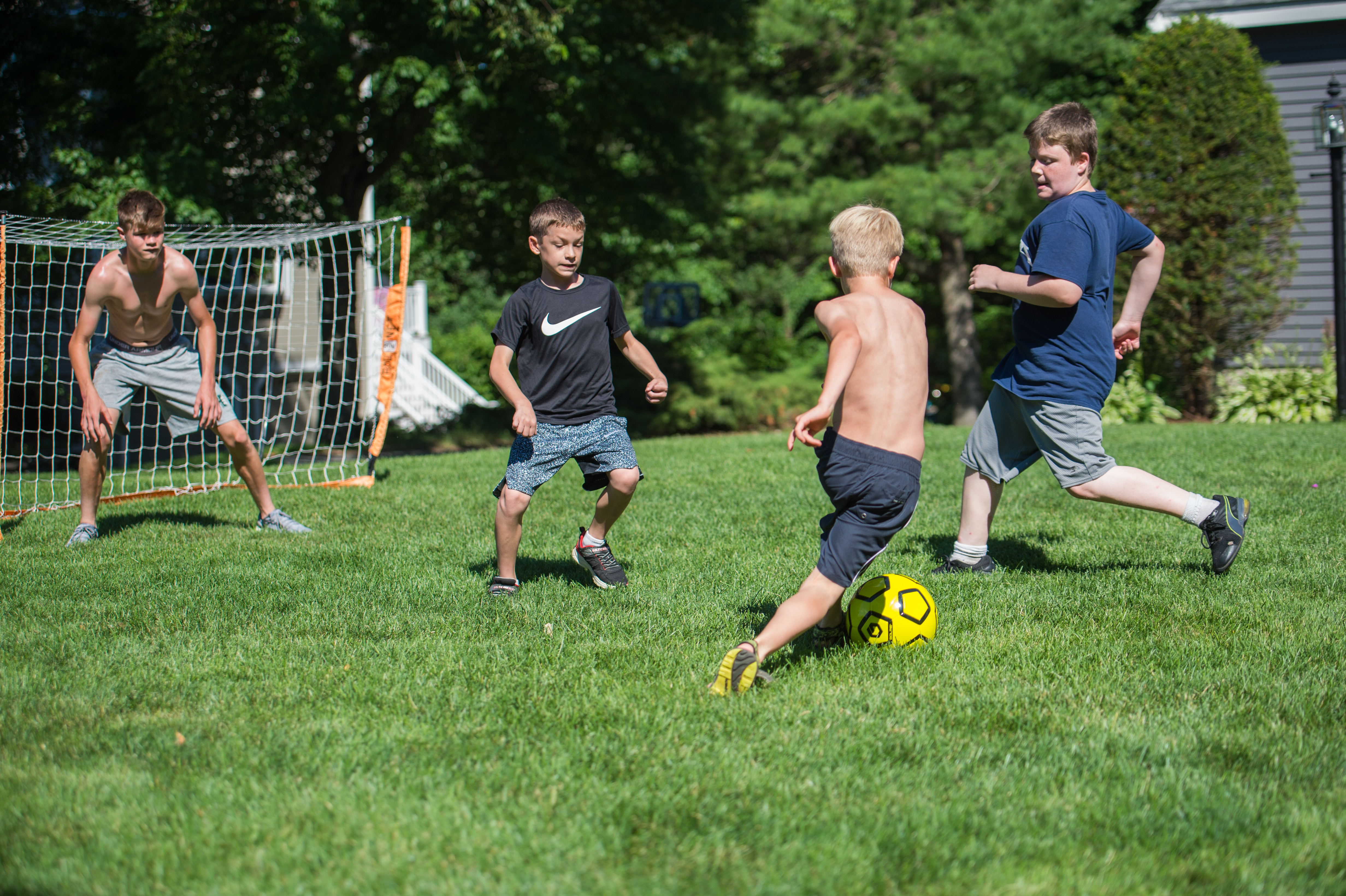 A group of boys play soccer on a grassy field, with Stan dribbling the ball while others defend.