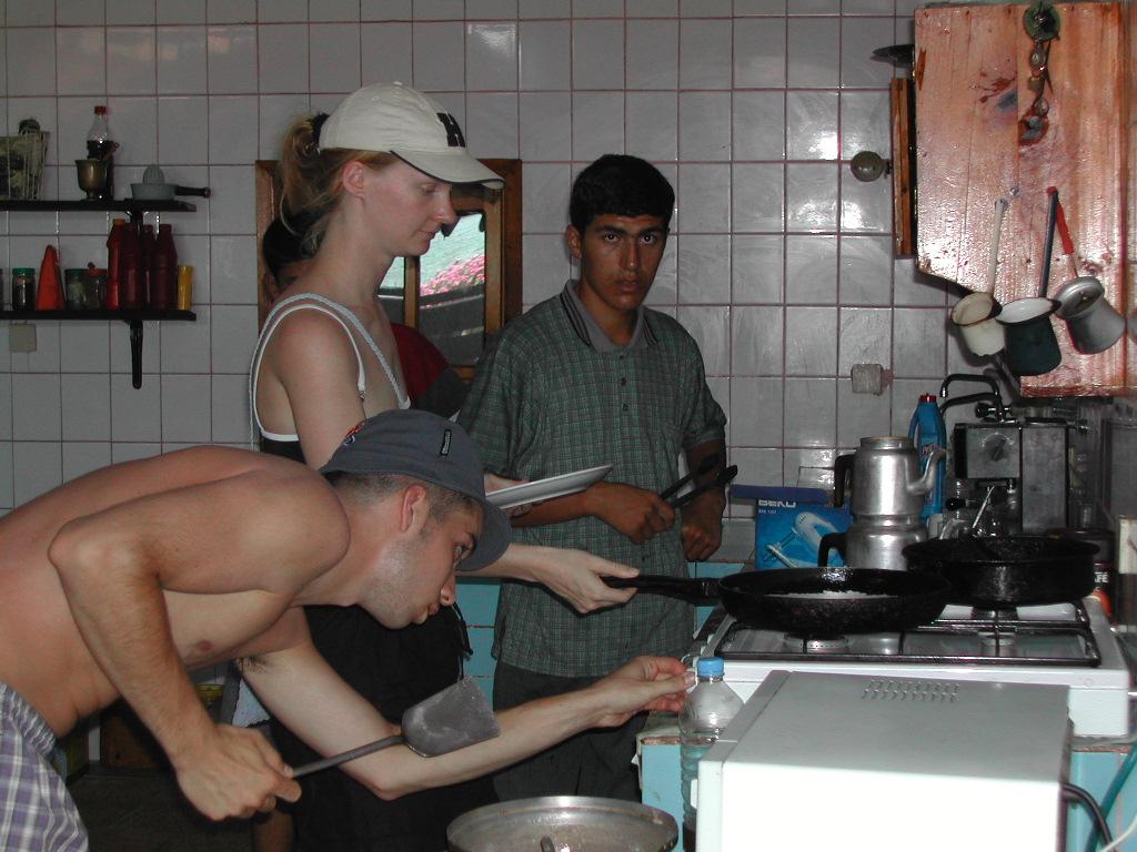 Three people are cooking in a kitchen.