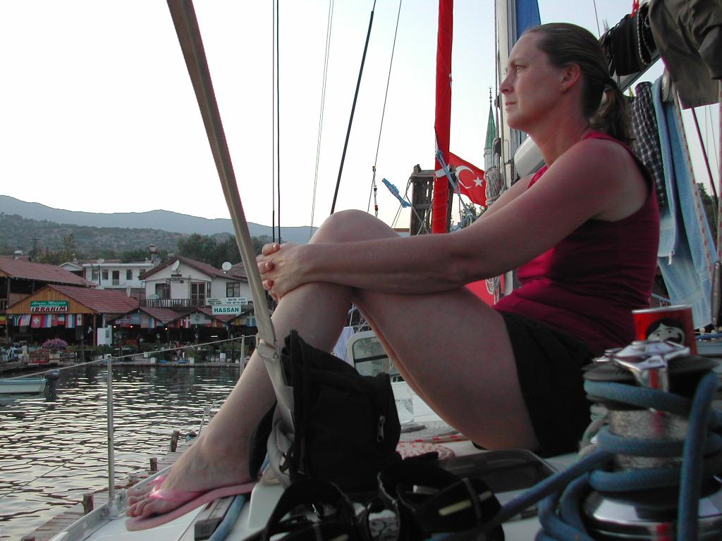 A woman sits on a boat, looking into the distance.