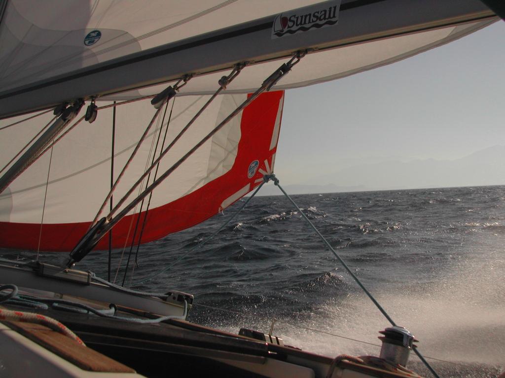 A sailboat moves through choppy waters with its sails fully extended, catching the wind.