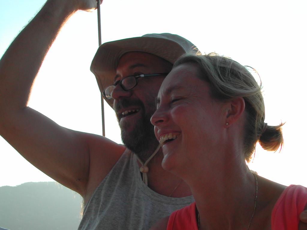 A man and woman smiling and laughing together, with the man raising his arm.