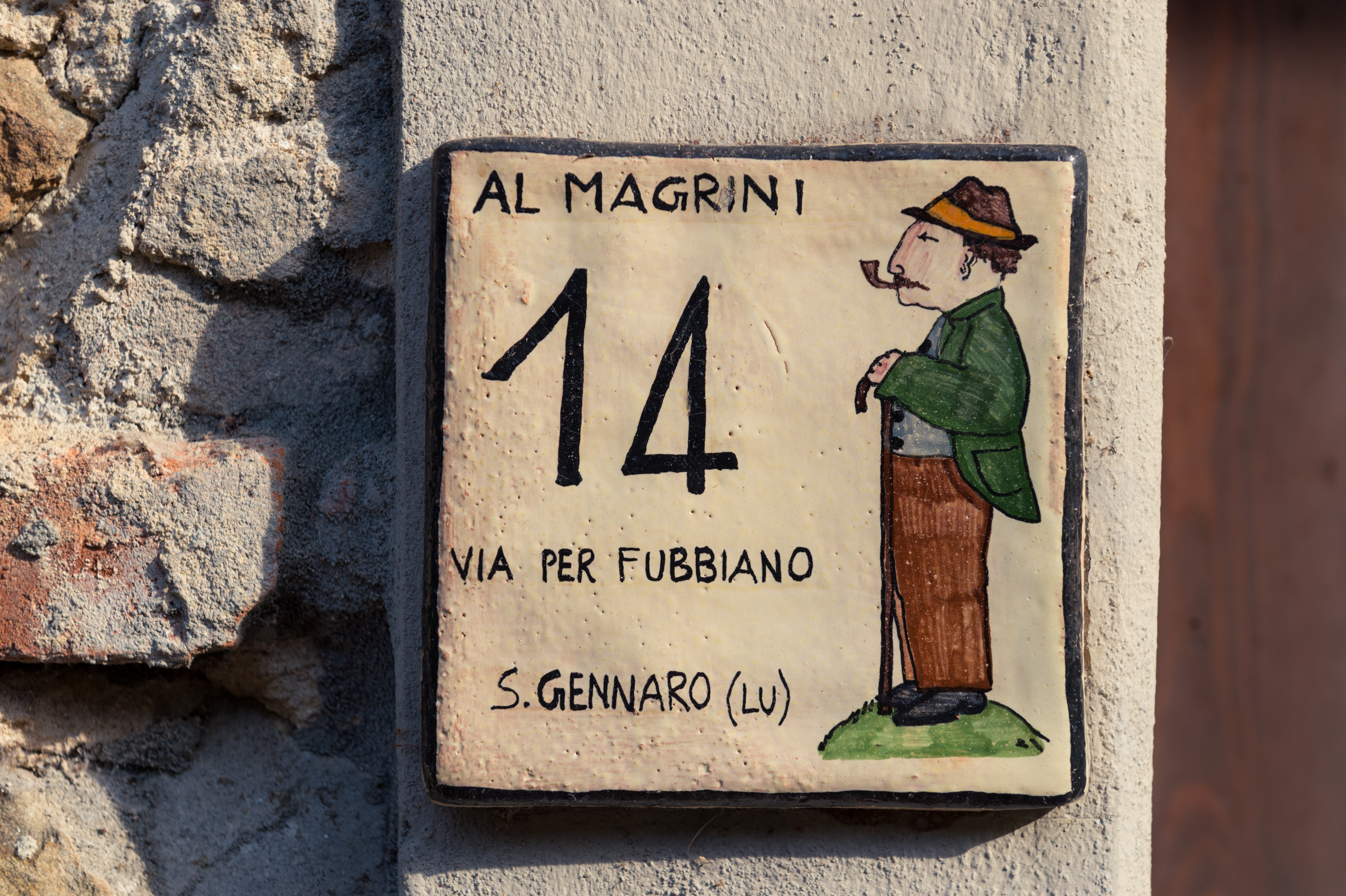 Ceramic house number sign reading "14" with an illustration of a man smoking a pipe, labeled "Al Magrini.