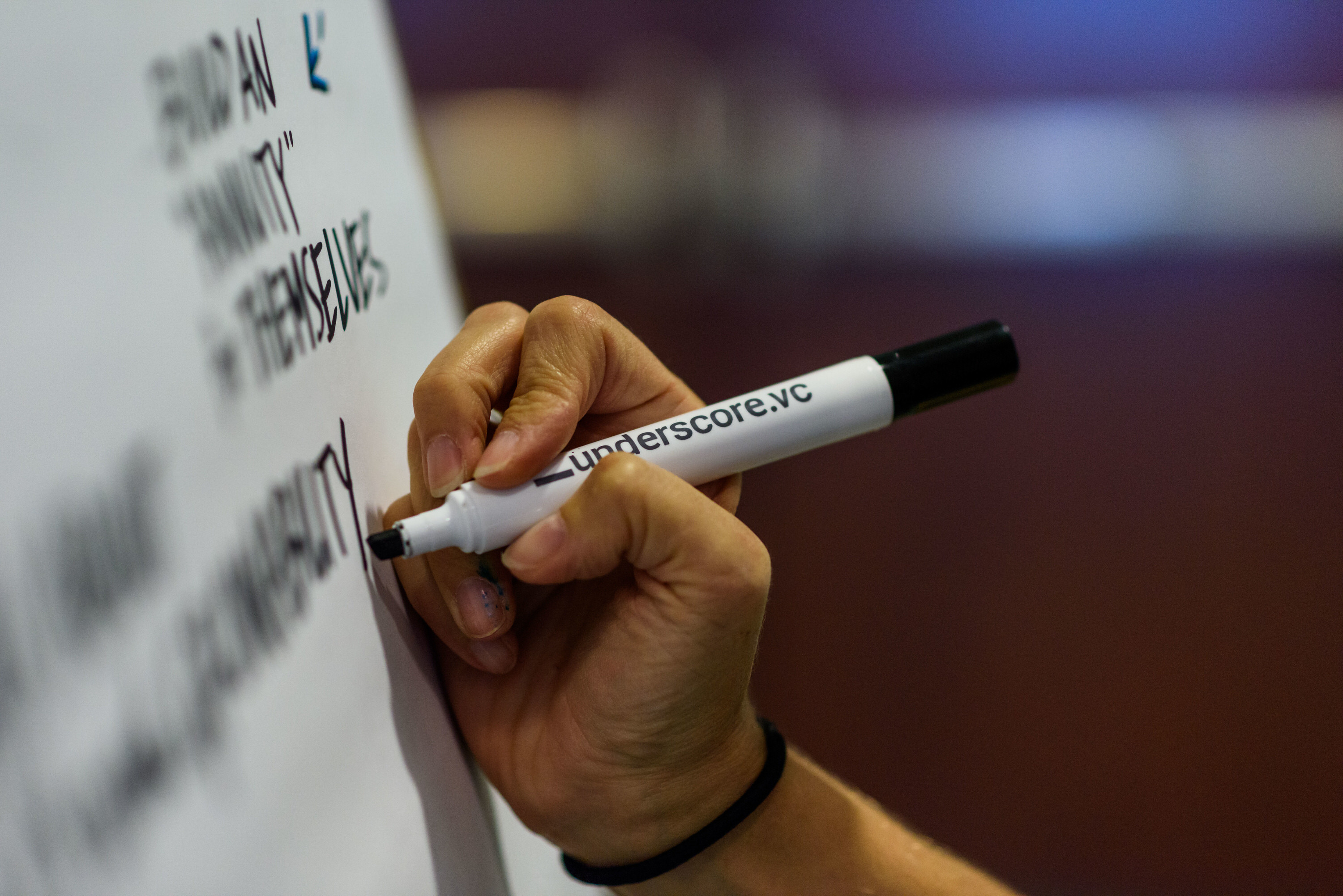 A hand writes on a whiteboard using a marker labeled "Underscore.