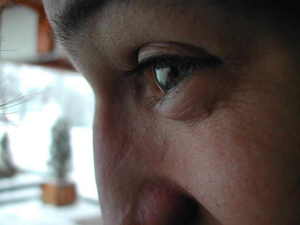 Close-up of a person's eye looking at a snowy outdoor scene, with reflections visible in the eye.