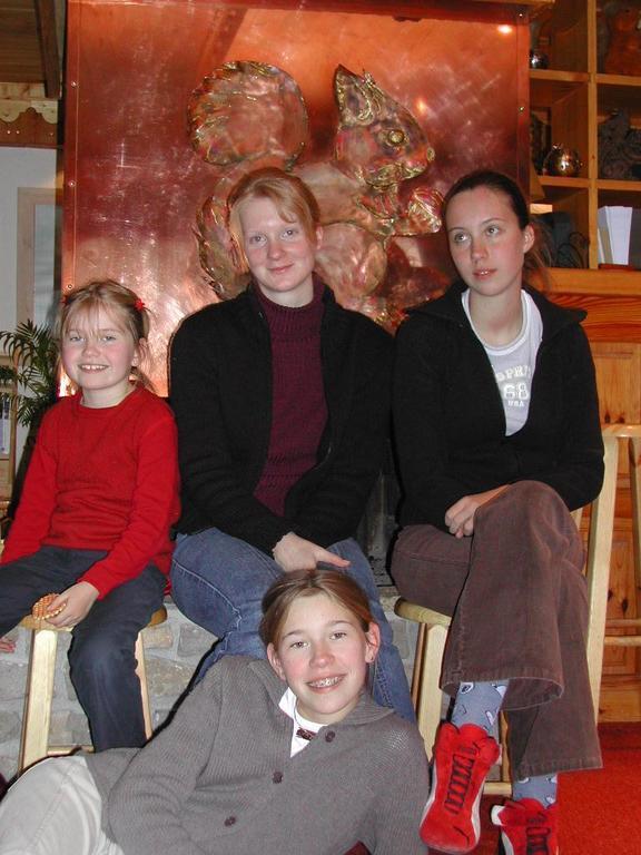 Four people sit and pose for a photo indoors, with a large decorative squirrel artwork behind them.