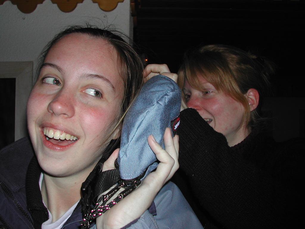 Two people laughing as one playfully holds a small bag to the other's head.