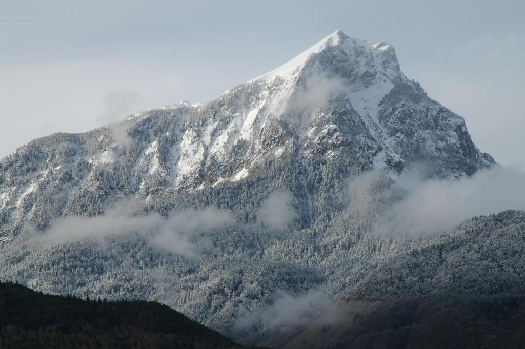 Snow-covered mountain peak with patches of clouds surrounding the slopes.