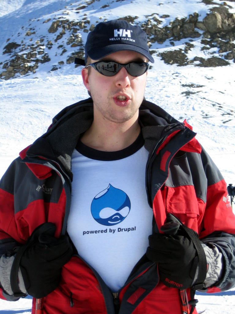 Person in winter gear opens jacket to reveal a "Powered by Drupal" T-shirt, promoting the Drupal platform.