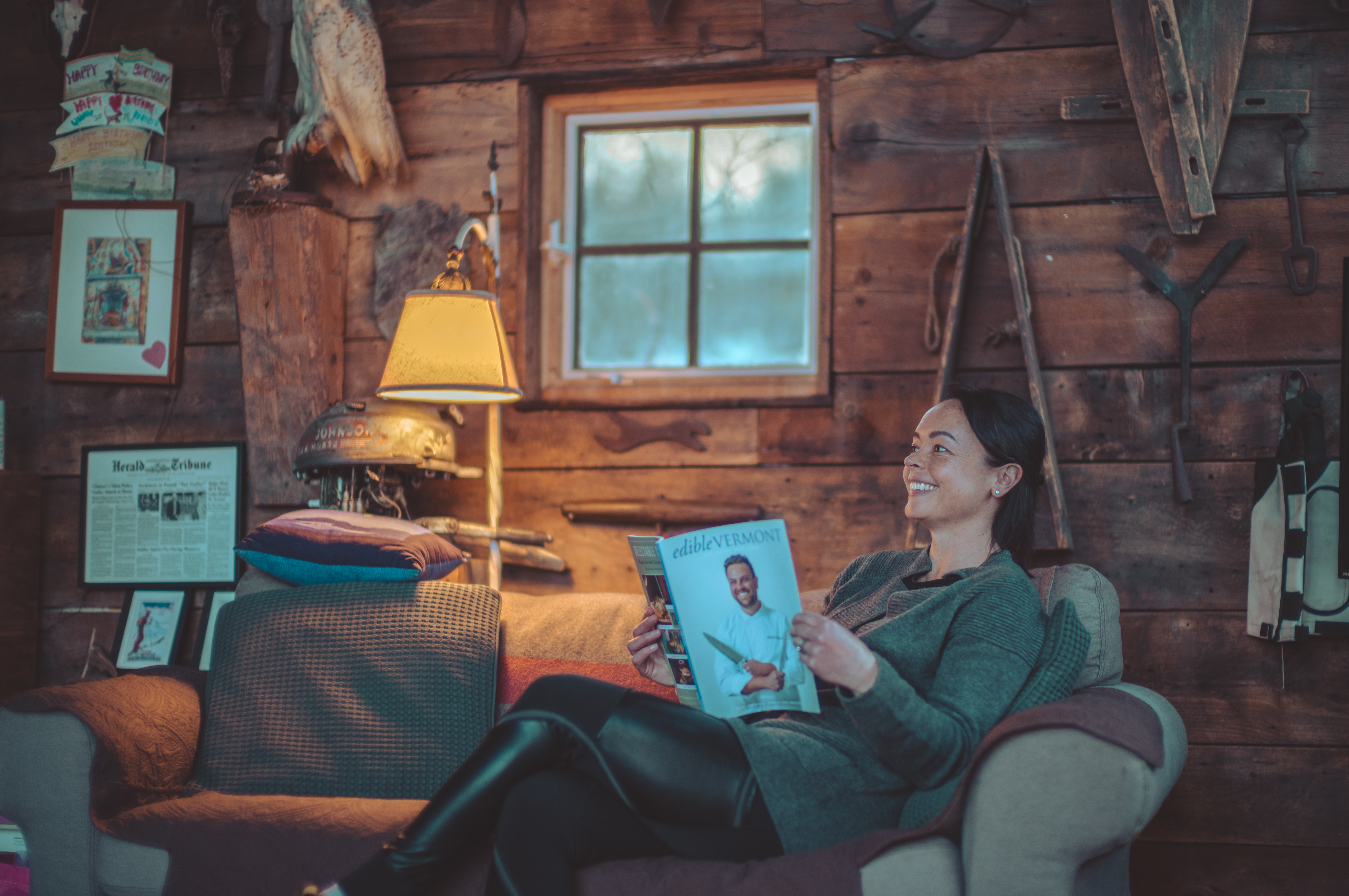A woman sitting on a sofa reading a magazine.