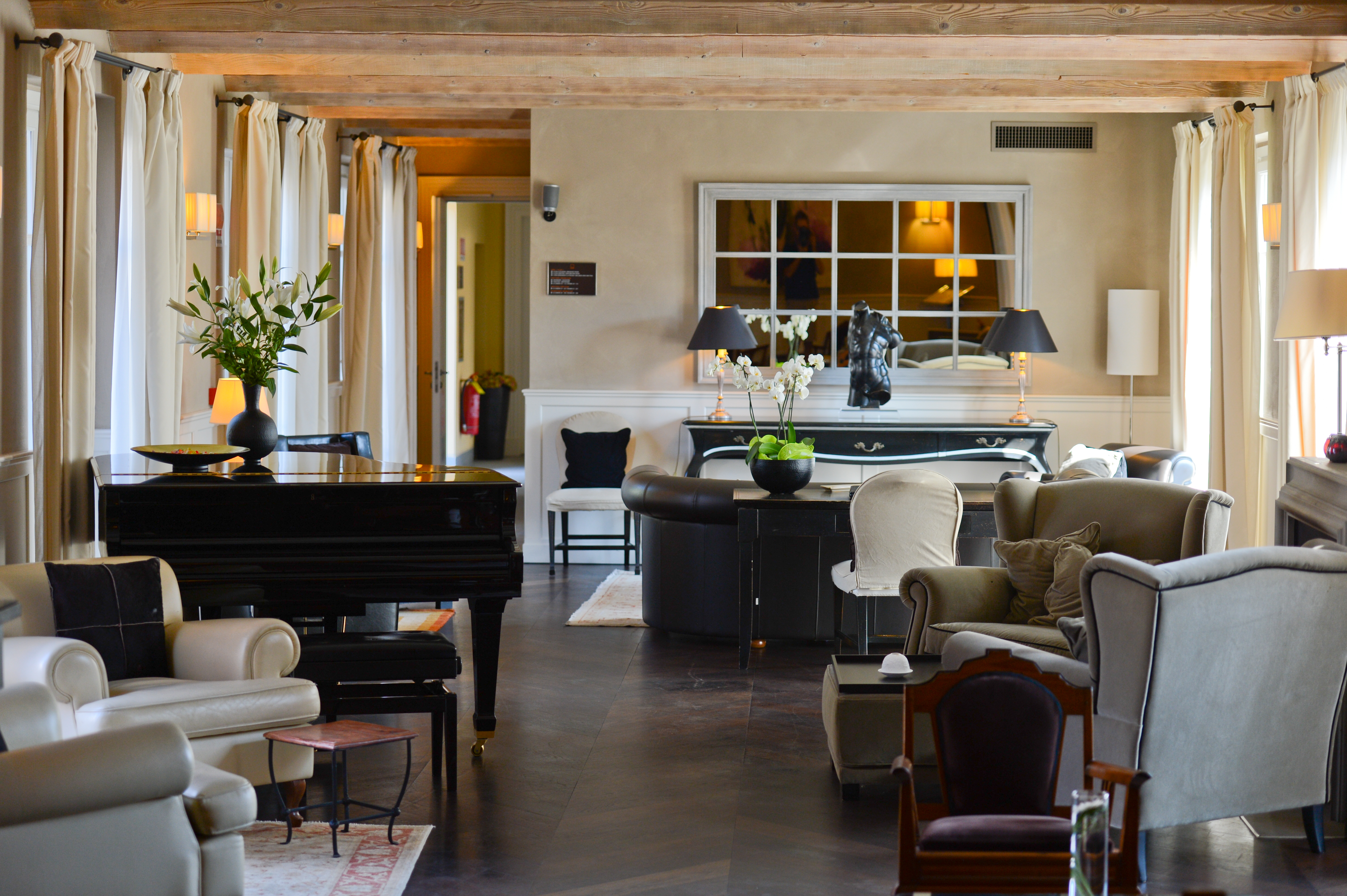 A well-decorated lounge with a black grand piano, elegant furniture, and soft lighting.