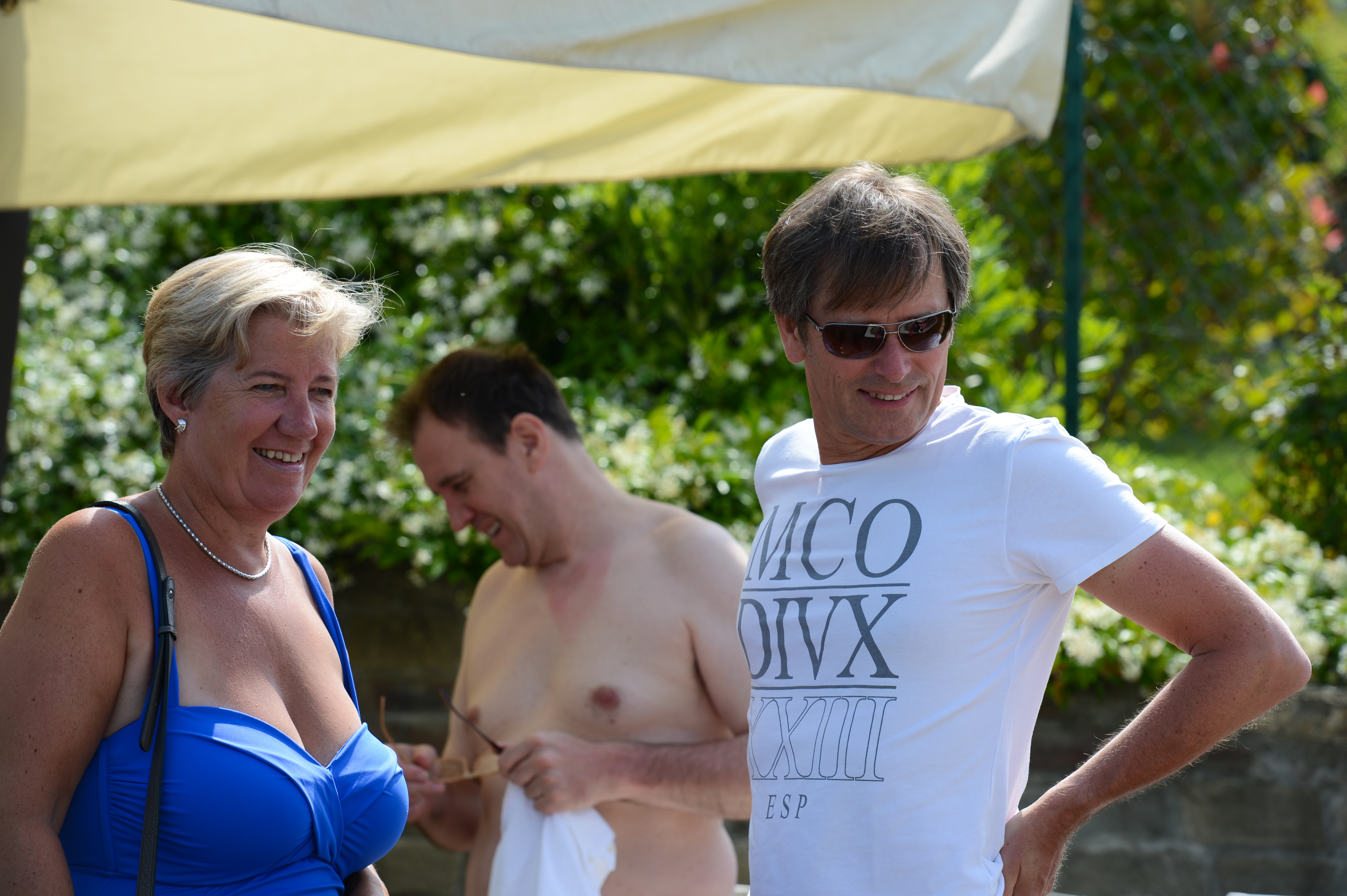 Three people outdoors, smiling and chatting.