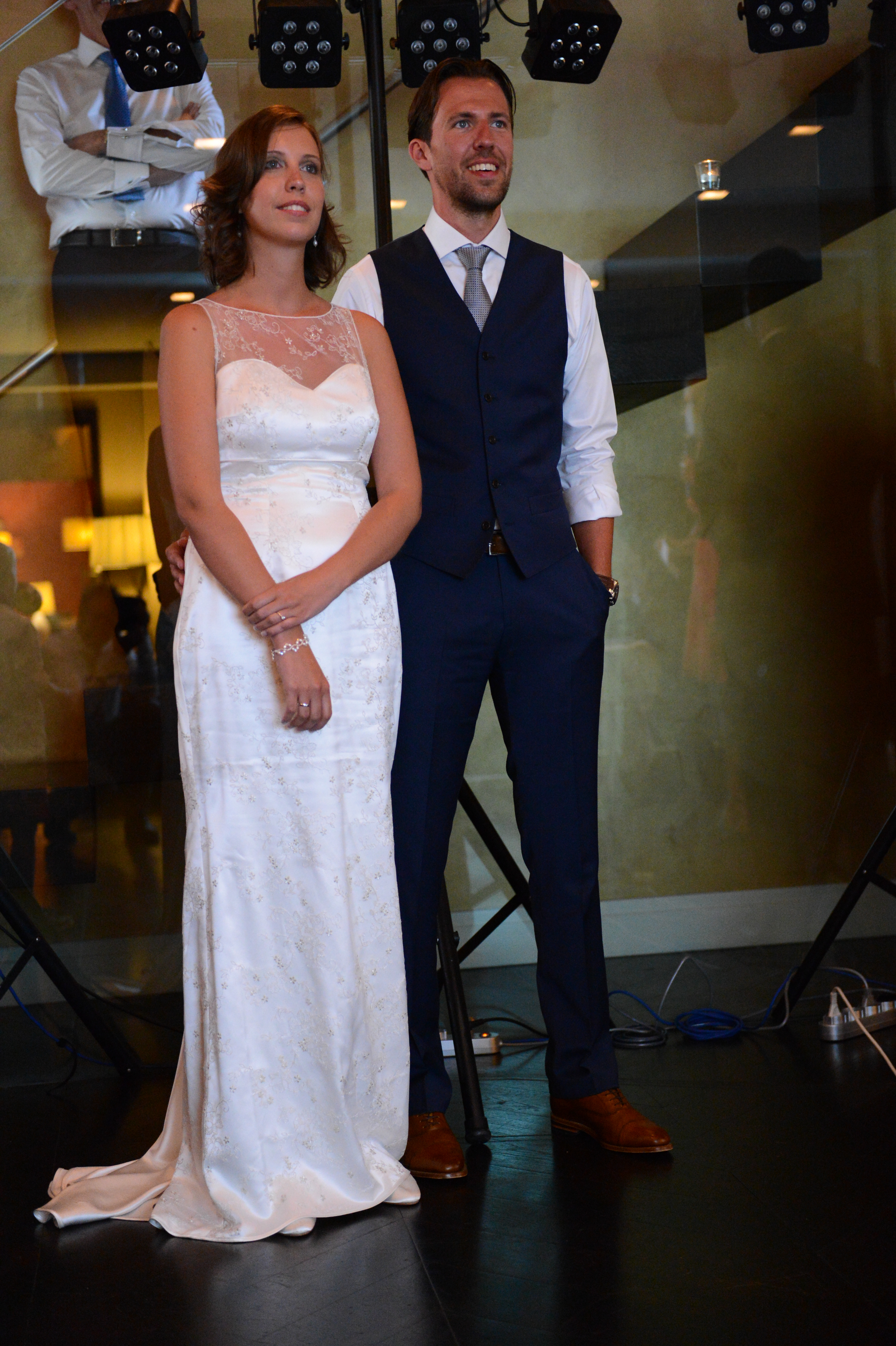 A bride and groom stand together, smiling and looking ahead during their wedding celebration.