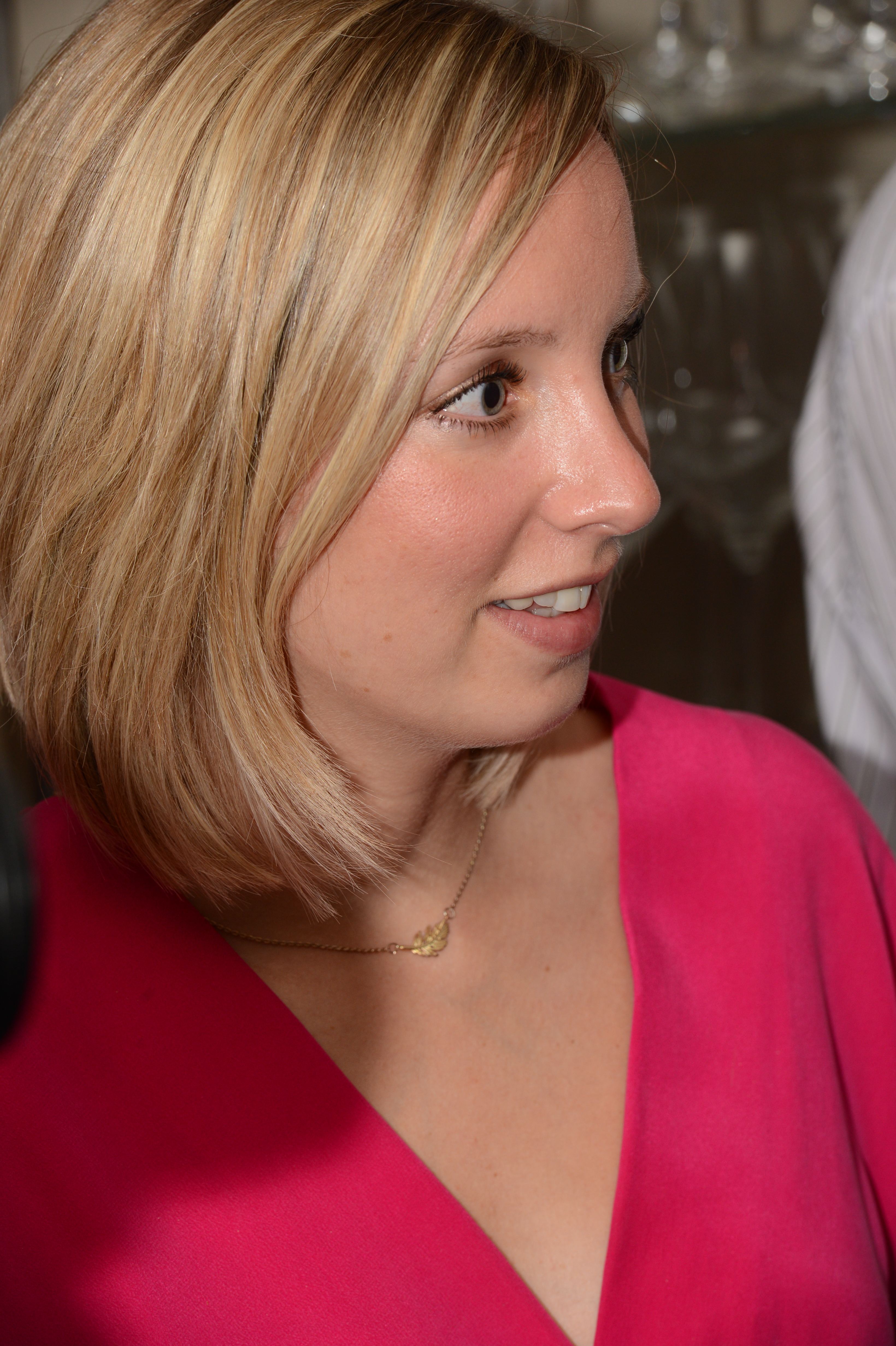 A woman in a pink dress looks to the side at a wedding reception.