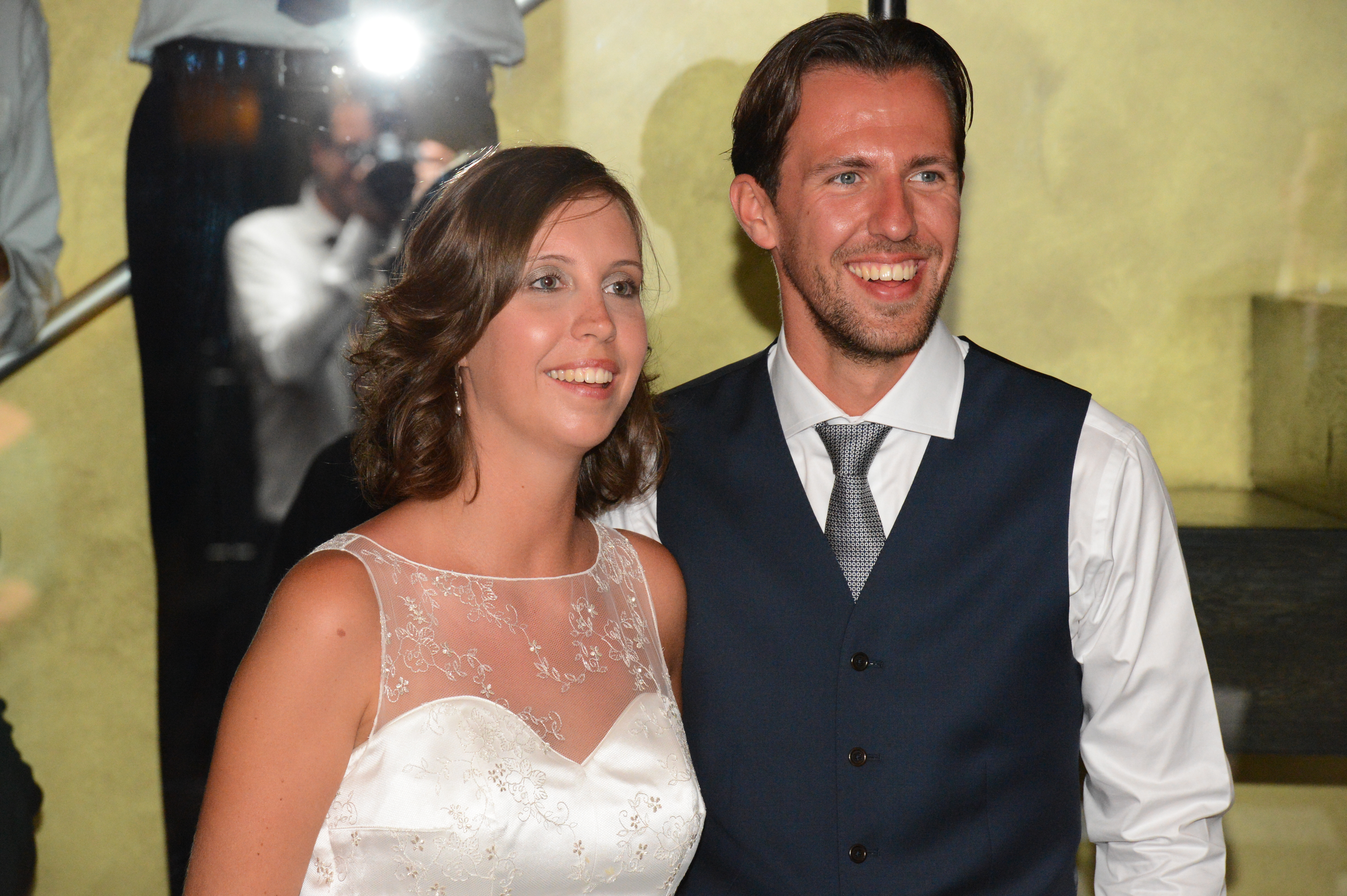 A bride and groom smile while posing for a photo at their wedding.