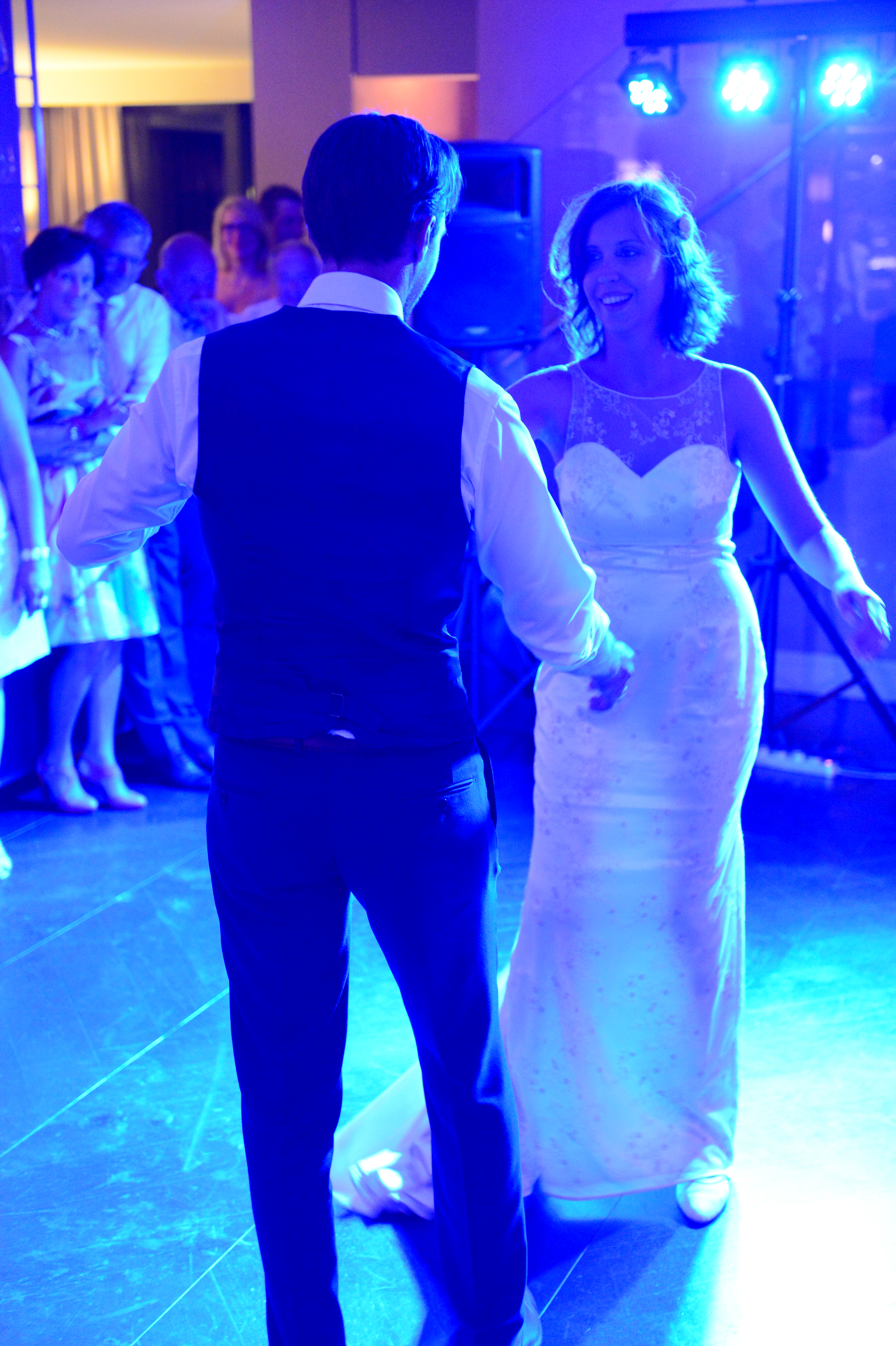 A bride and groom share their first dance at their wedding, surrounded by guests watching and celebrating.