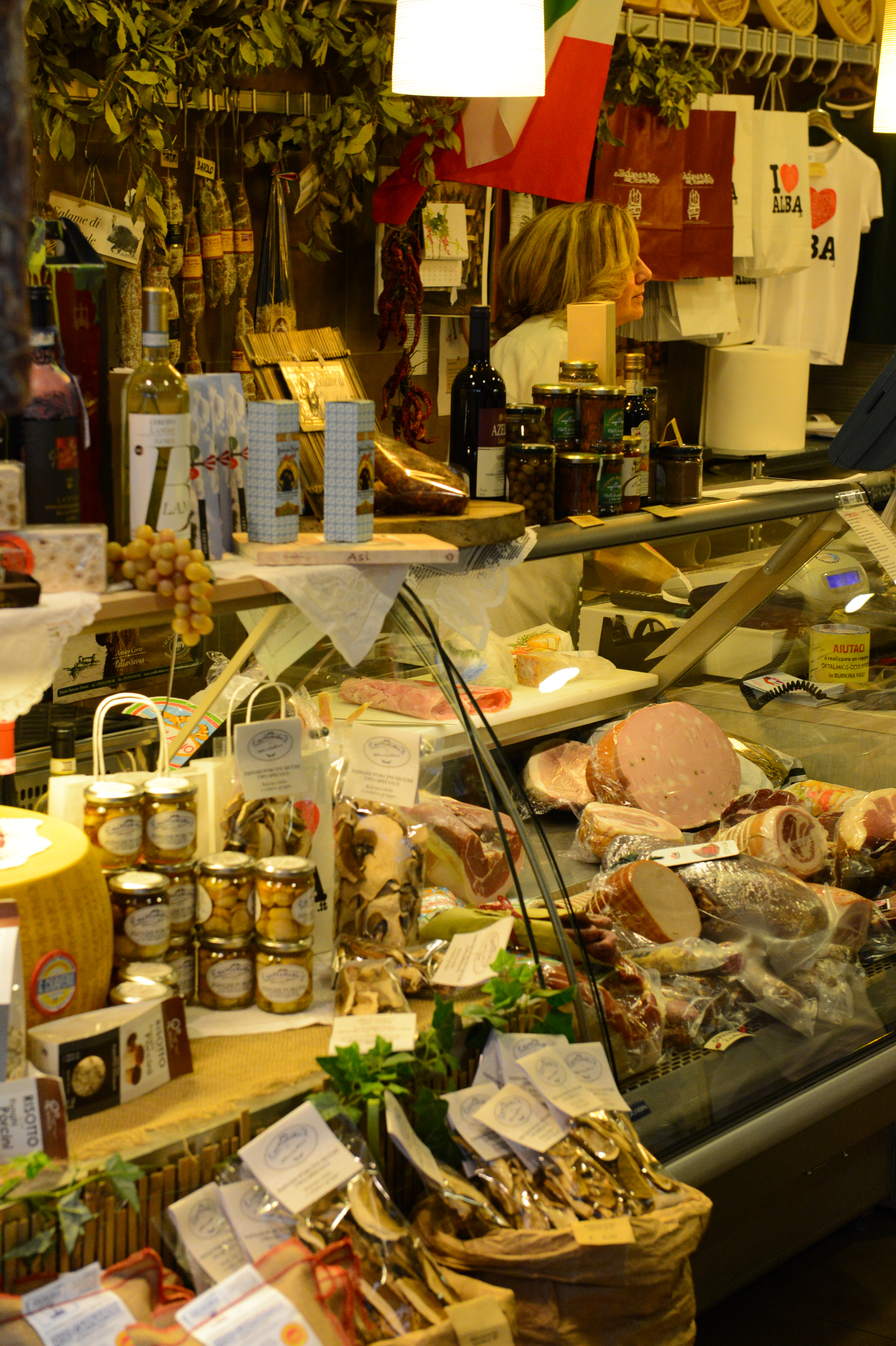 A deli shop with a glass counter displaying meats, cheeses, and jars of preserved food.