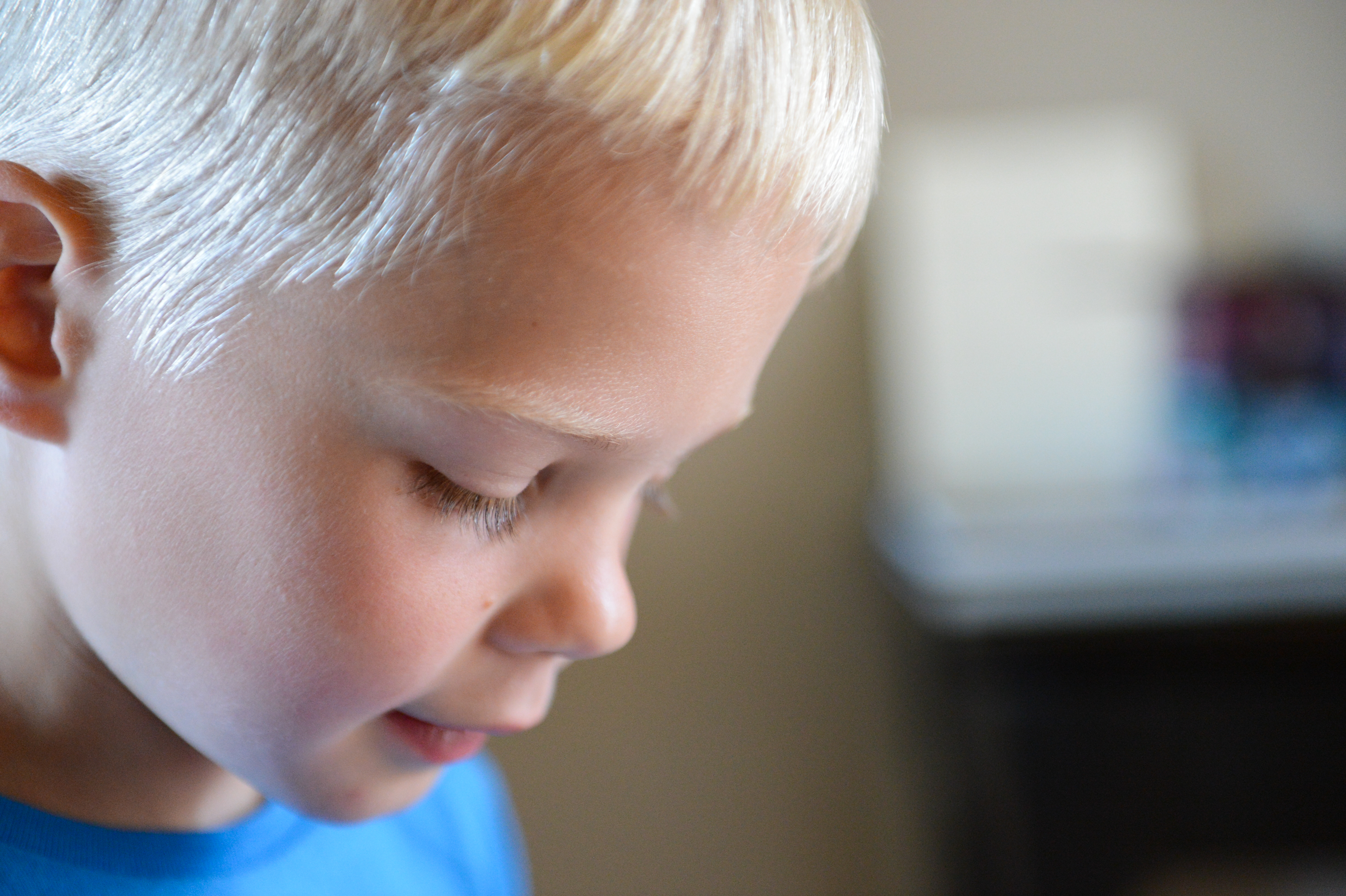 A young child in a blue shirt looks down with a focused expression at a wedding event.