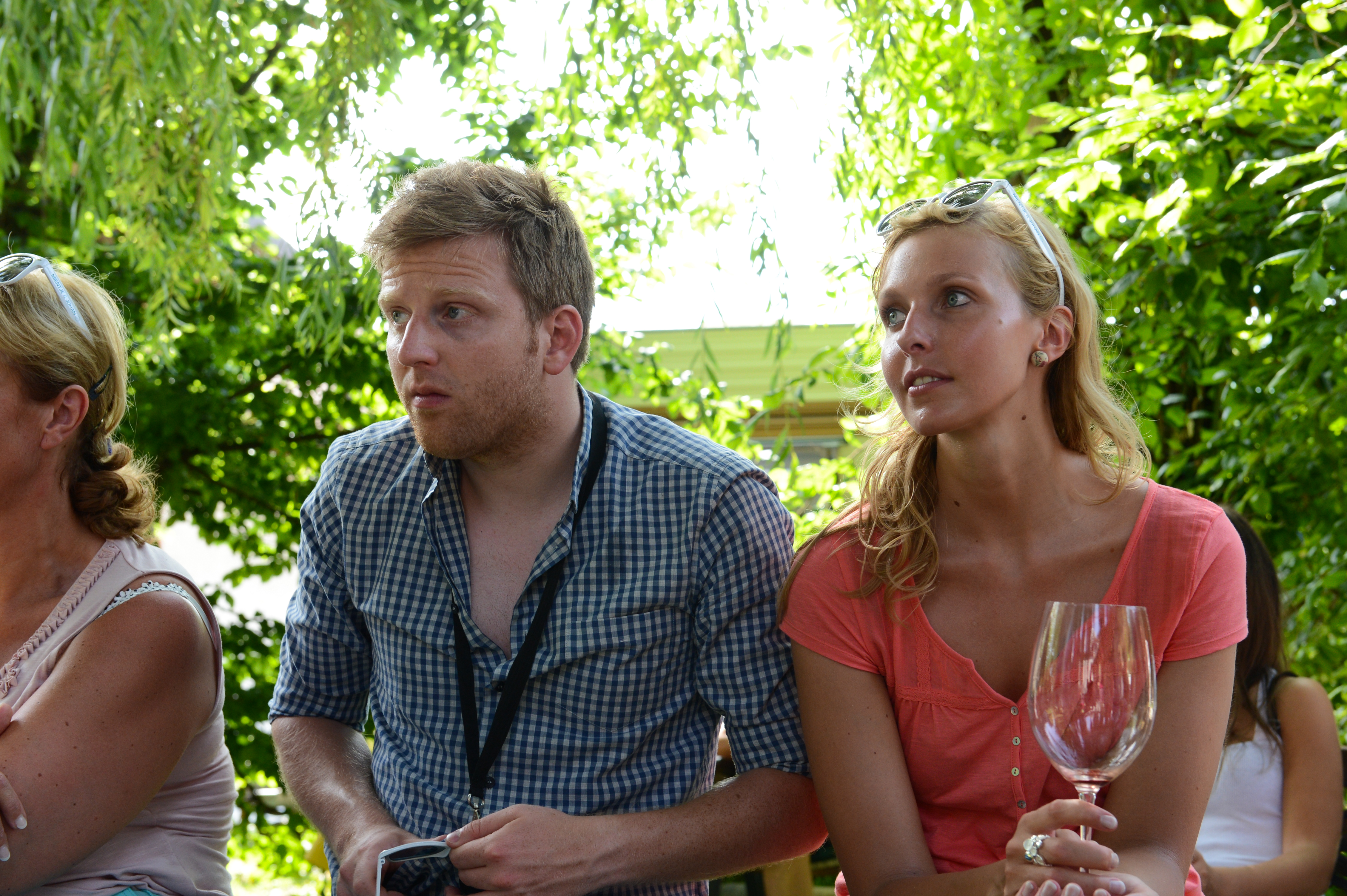Two people sitting outdoors at a wedding, attentively listening.