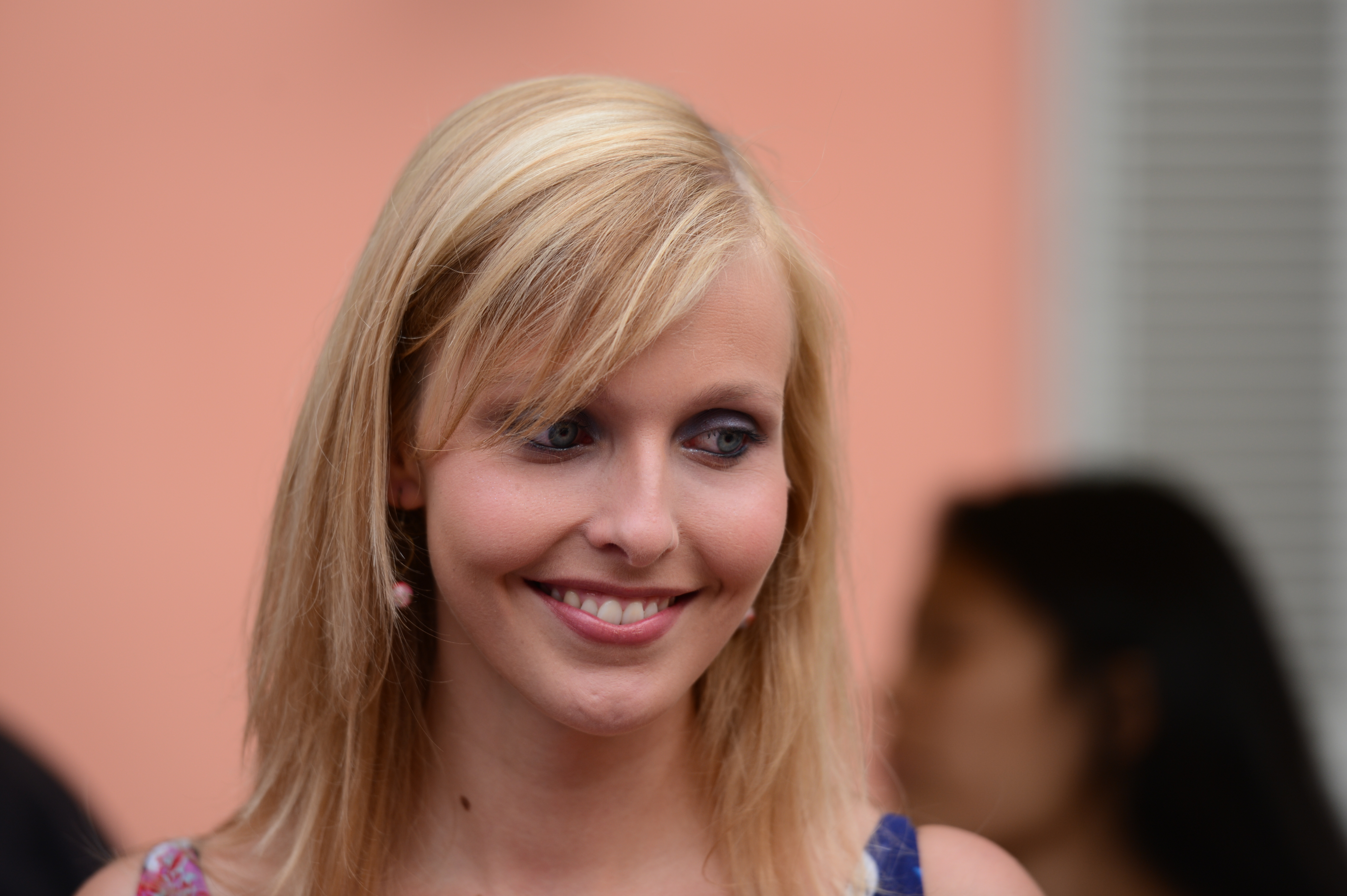 A woman with blonde hair smiles while looking to the side at a wedding event.