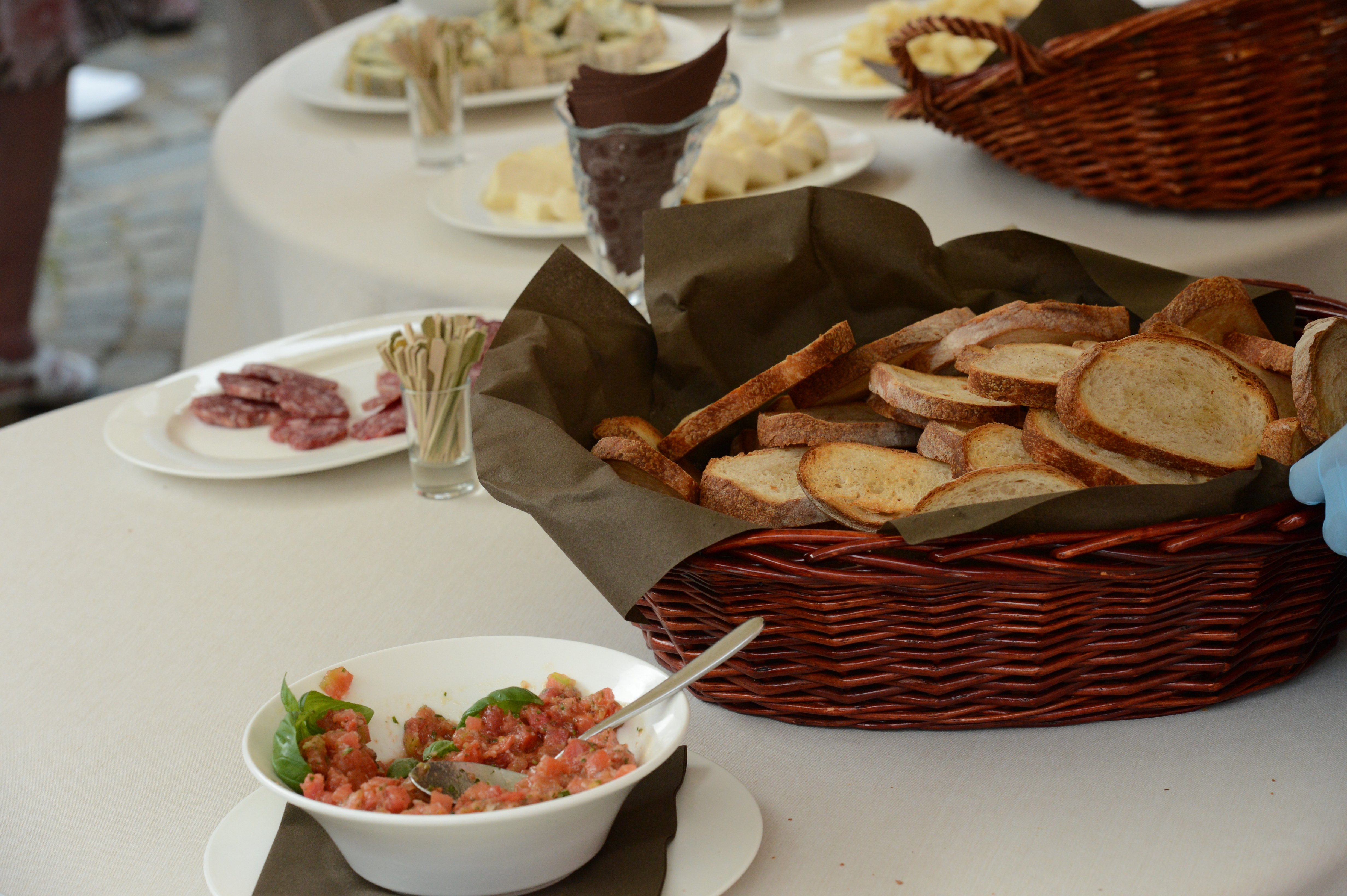A wedding buffet table with a basket of toasted bread, a bowl of tomato mixture, and plates of appetizers.