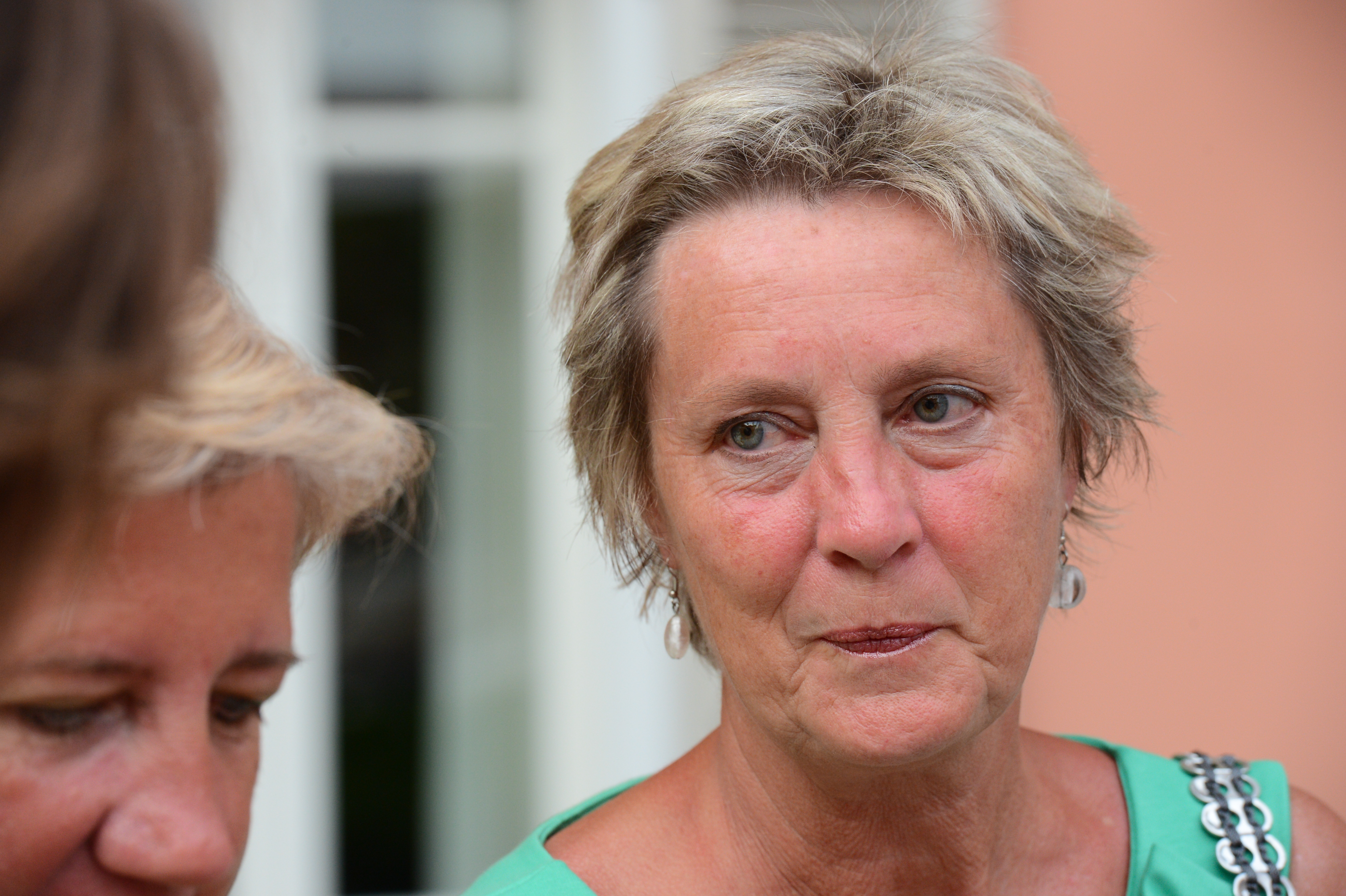 A woman in a green dress listens attentively while another person speaks at a wedding gathering.