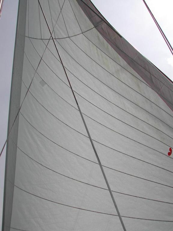 A close-up view of a sail on a boat, stretched tight by the wind against the sky.